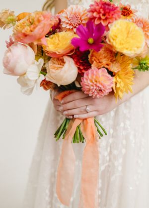 Colorful wedding bouquets with coral, peach and pink flowers tied with silk ribbons.