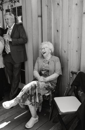 Black and white photograph of wedding guests sharing a candid laughing moment.