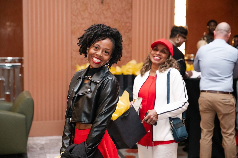 A group of people laughing and smiling together in a hallway with terracotta colored walls.