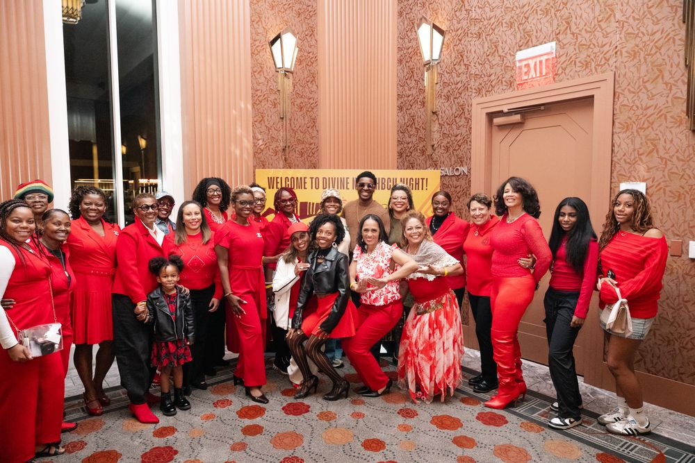 Large group of people wearing red shirts gathered in a hallway for a group photo.
