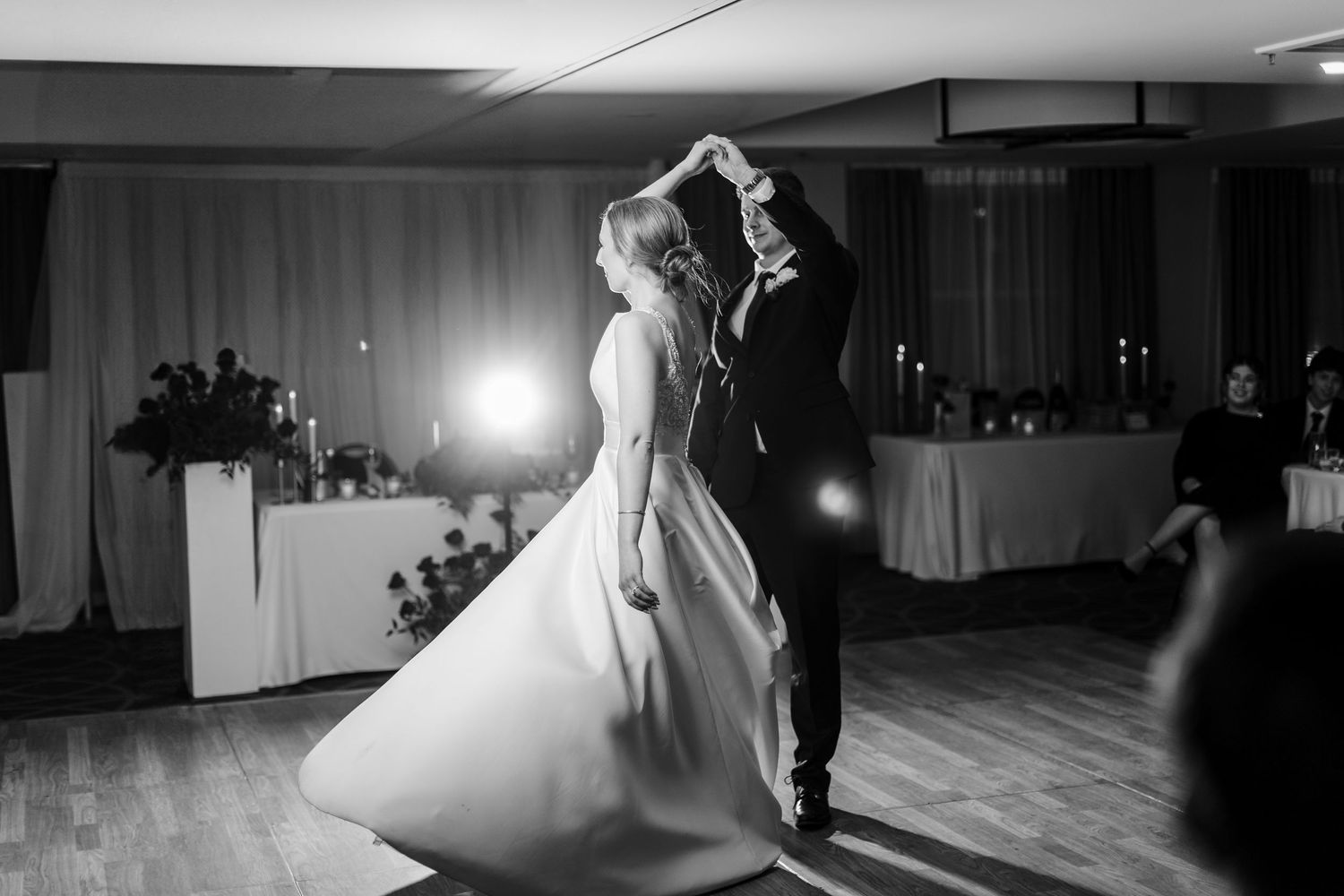 A couple dances together in an elegant ballroom setting during what appears to be their first wedding dance.