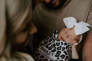 Artistic portrait of a sleeping infant with white bow and leopard print wrap.