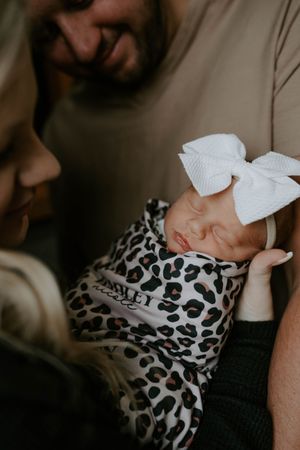 Intimate newborn photography with soft lighting showing baby in leopard print swaddle.