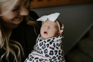 Sweet moment captured of newborn in white bow and animal print swaddle.