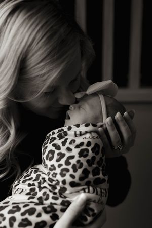 Black and white portrait of tender moment with newborn in leopard print wrap.