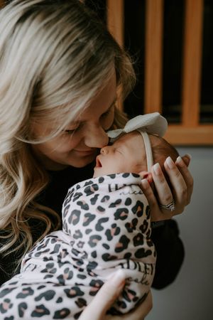 Intimate lifestyle photo of tender moment with sleeping newborn in animal print.