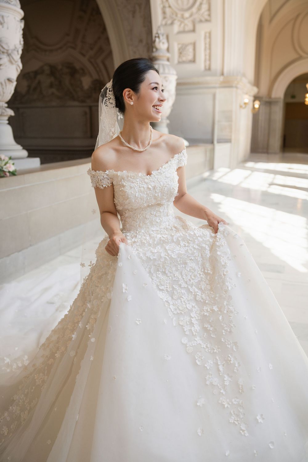 Stunning white ballgown wedding dress with intricate floral lace details and flowing train in elegant venue.