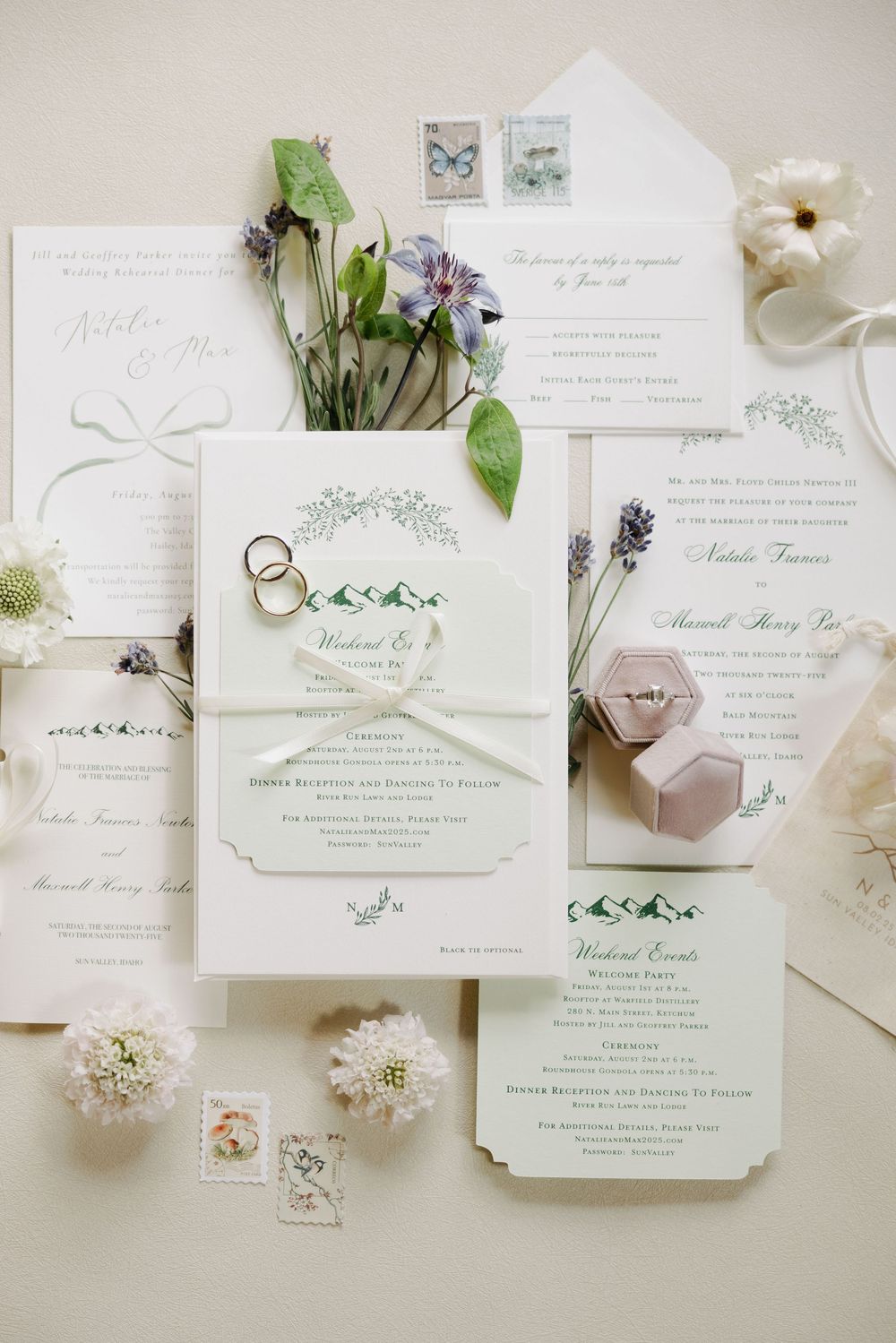 Elegant wedding stationery flat lay with floral details, rings, and delicate invitations in soft white and green tones.