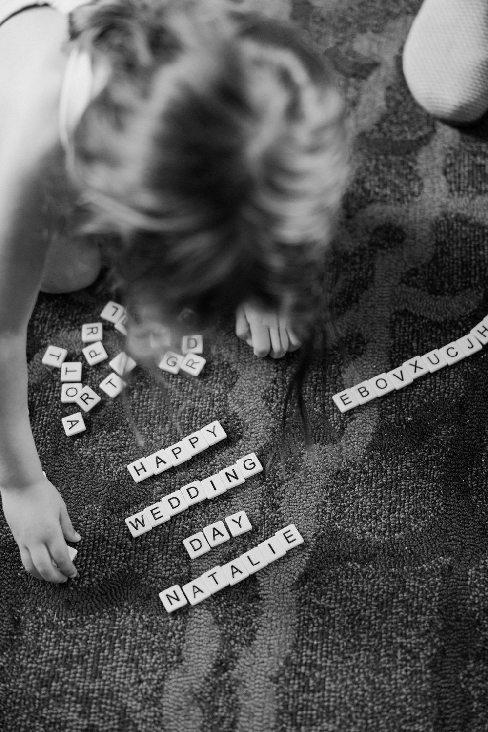 Black and white photo series showing letter tiles being arranged to spell out different phrases on a dark textured surface.