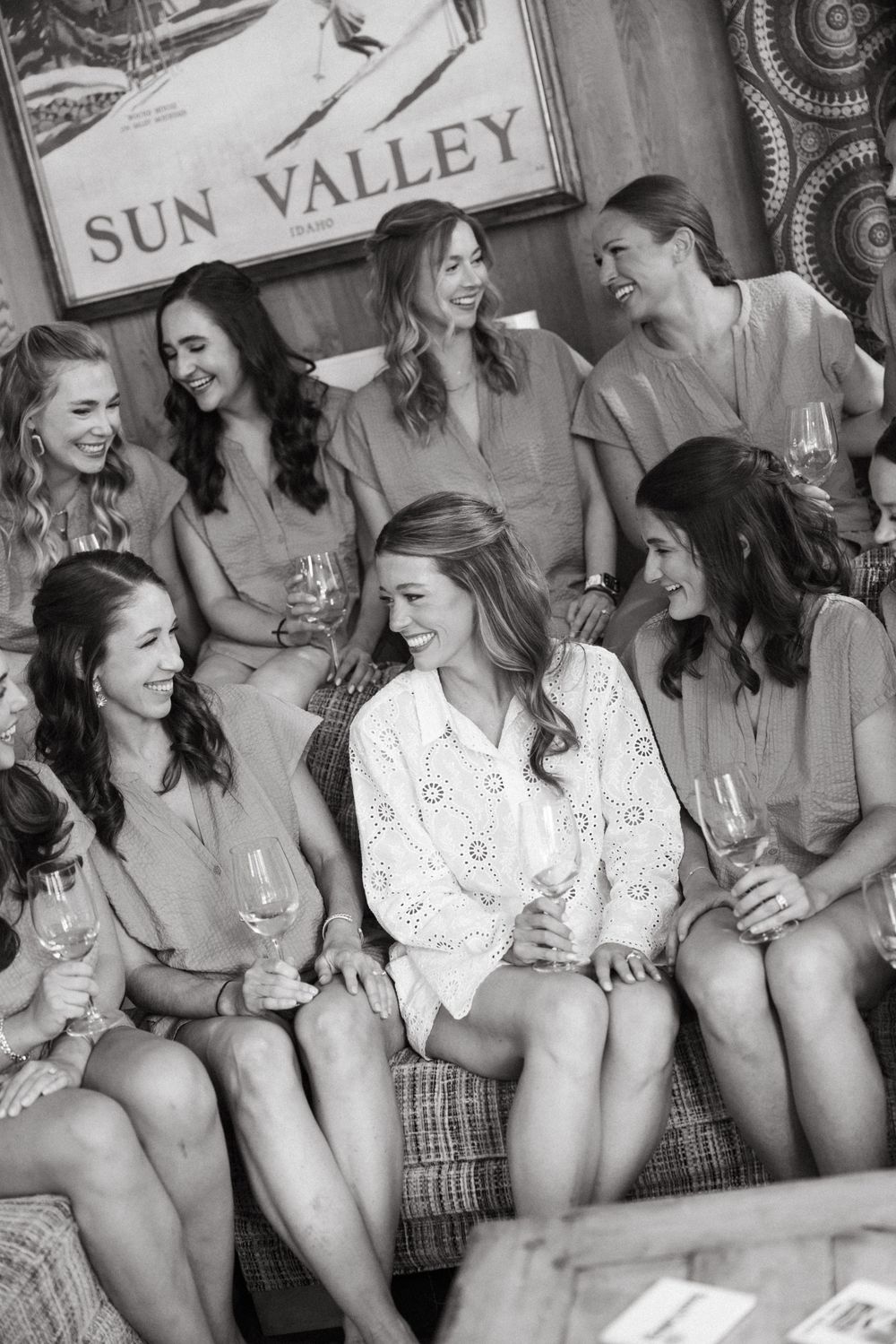 A black and white vintage photograph shows several women in swimsuits sitting together and laughing at Sun Valley resort.