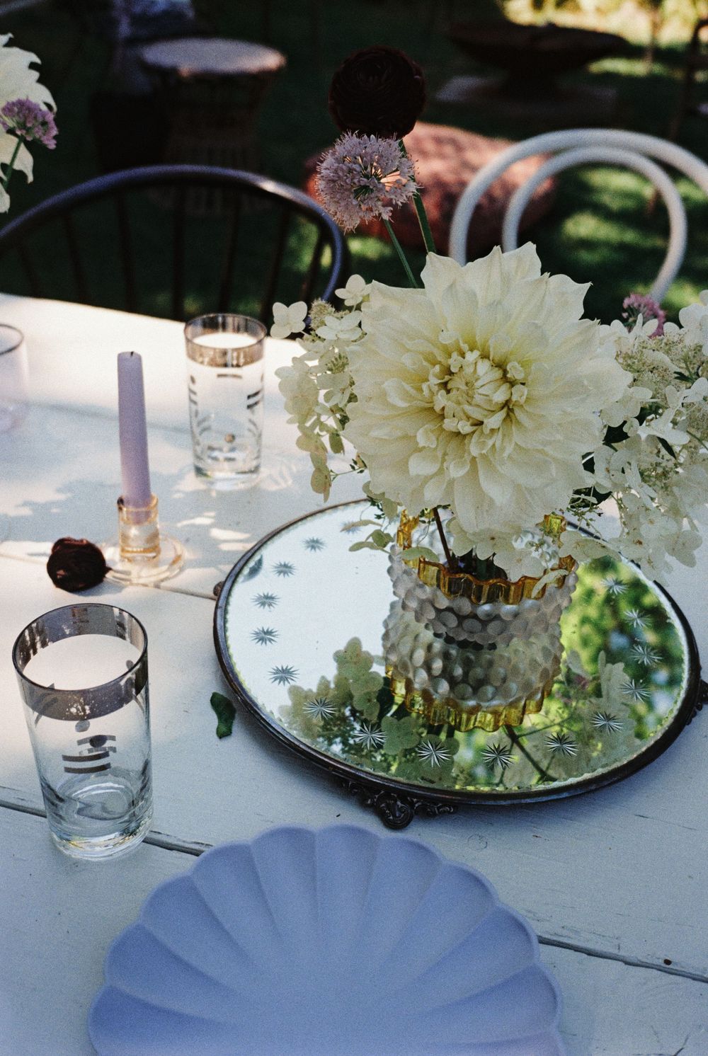 Bountiful cream flower arrangement in vintage glass on mirror tray and decorative design tablescape with lilac pastel plates and pink candle