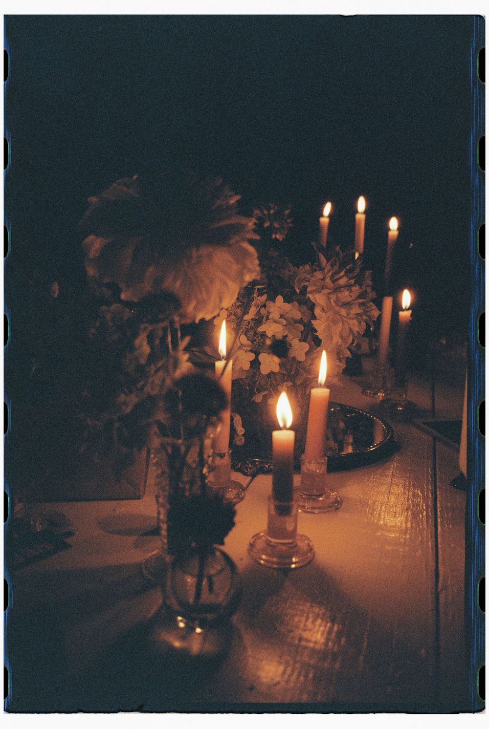 Table setting in the late evening with glowing candles and dimly lit flowers after a baby's sprinkle celebration in the late summer in Maine