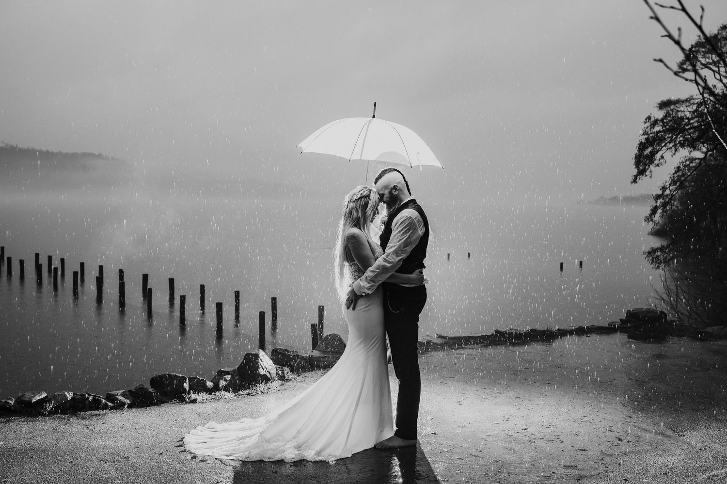 A romantic black and white wedding photo series showing couples embracing by a misty lake.