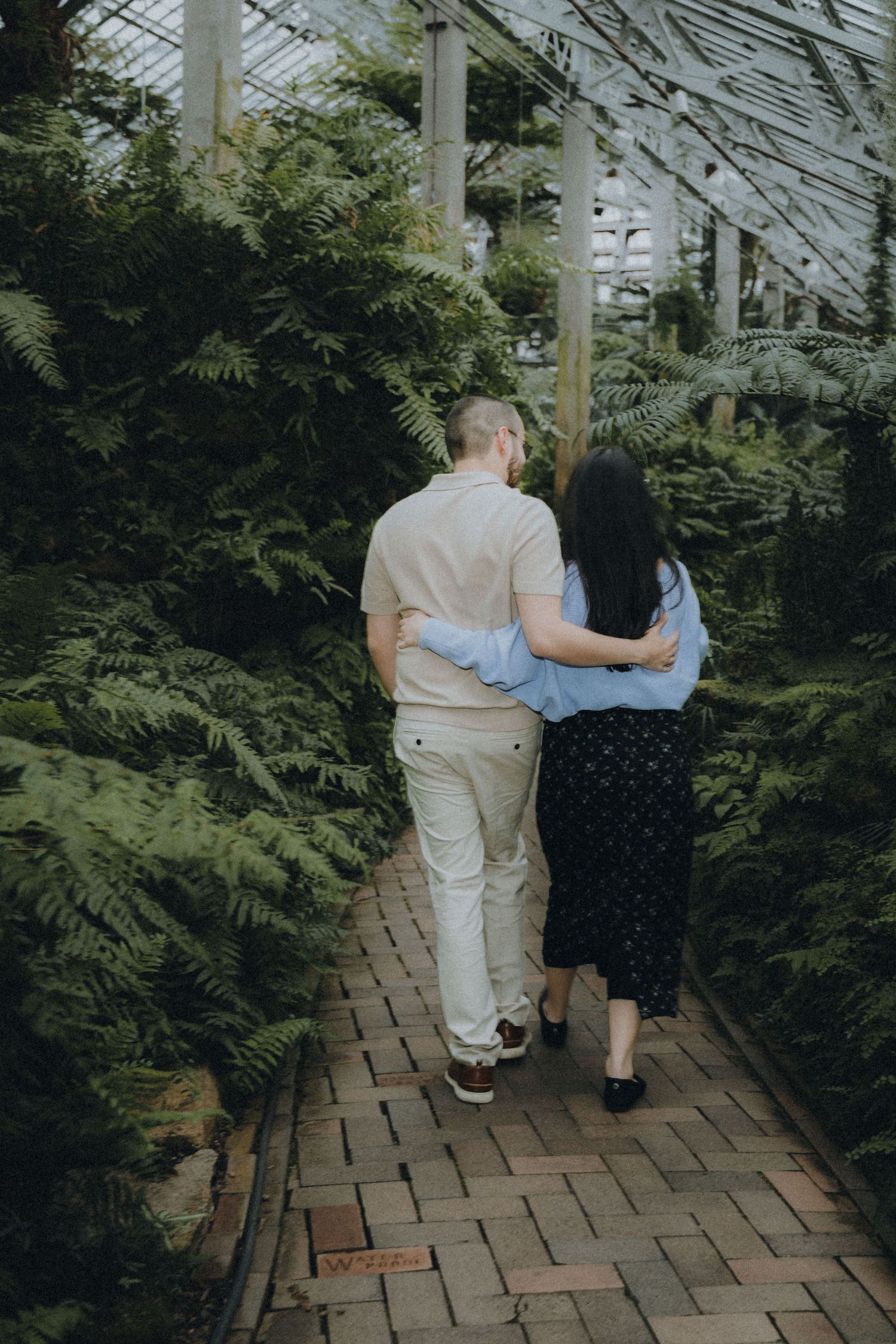 Server in black uniform standing at bar counter in modern restaurant interior.