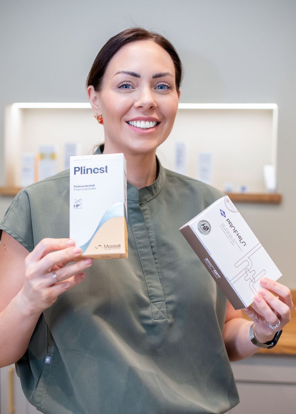Healthcare professional in scrubs displays various medical product boxes in a clinical setting.