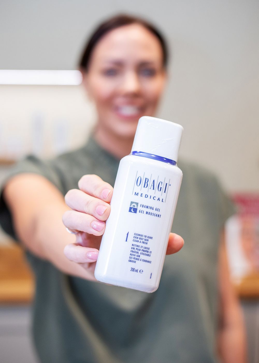 Close-up shots of hands holding white skincare product bottles against a light background.