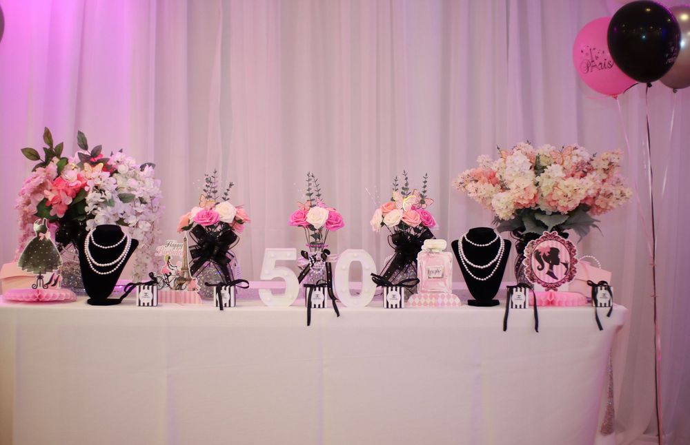 Pink and white floral arrangements with jewelry displays create an elegant bridal or wedding showcase setup.