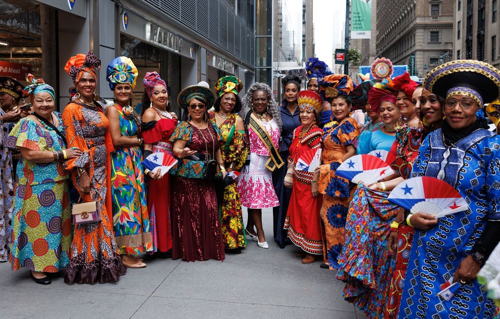 Large group of dancers in colorful traditional costumes performing at a cultural festival in an urban setting.