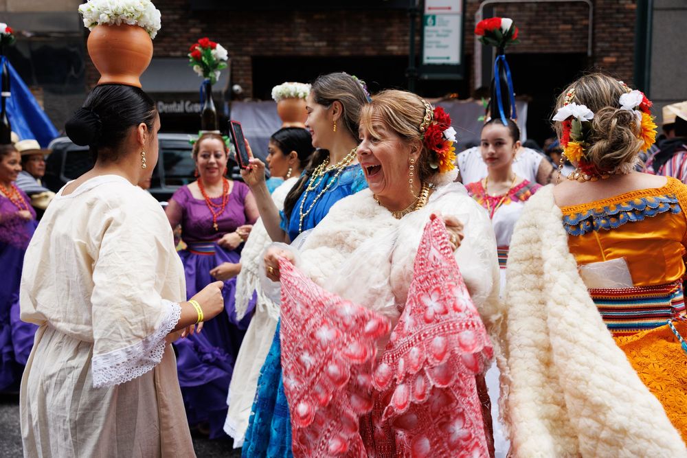 Performers wearing white and pink traditional outfits gather during a cultural celebration event.