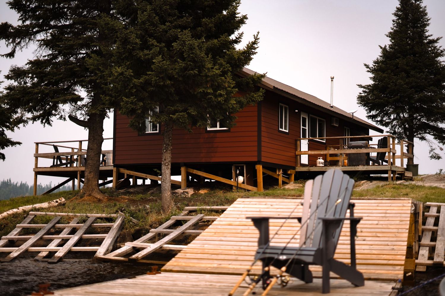 Construction of a wooden deck or platform between pine trees at a lakeside property.