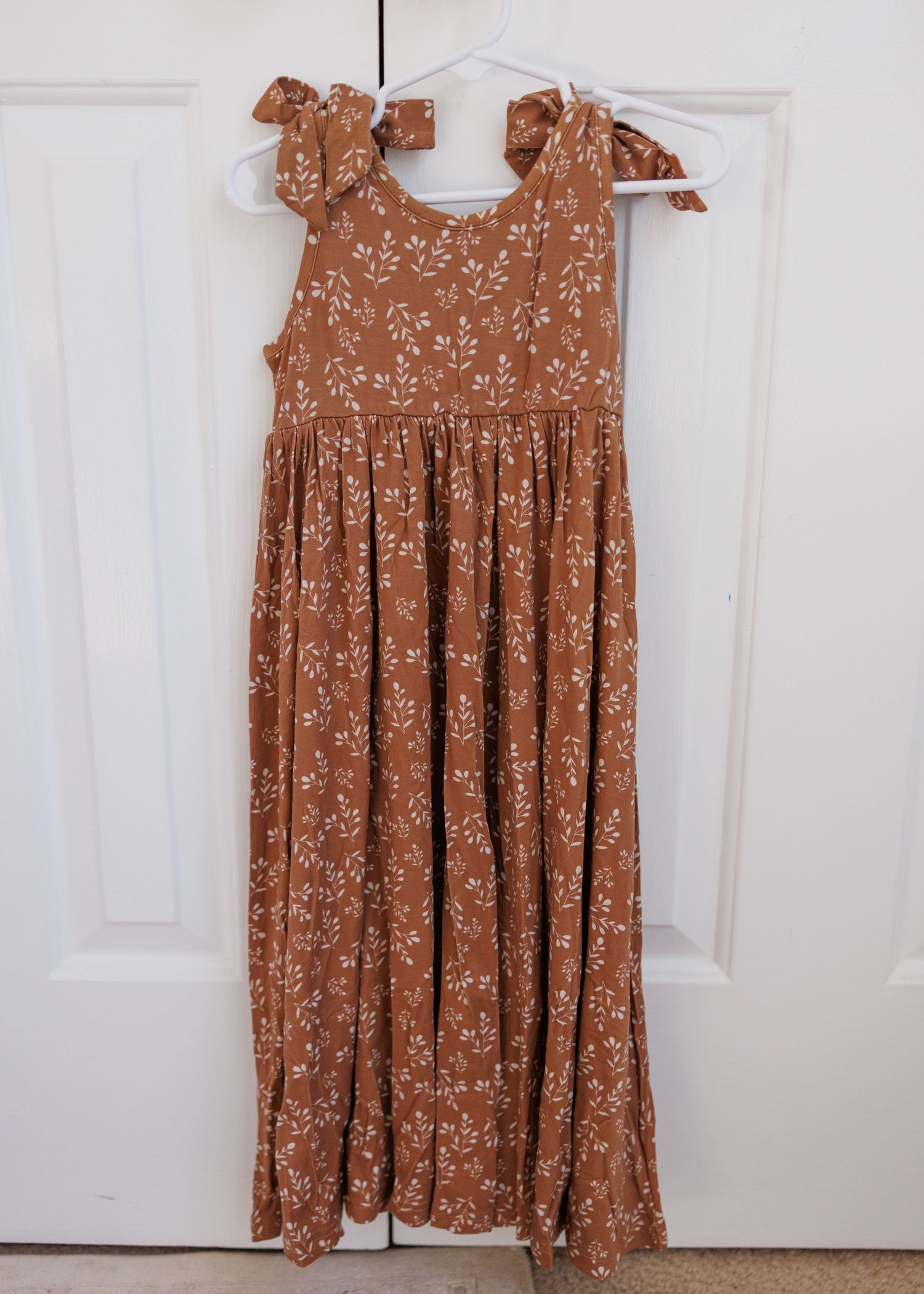 A floral print baby sleeper garment with red and brown pattern shown from multiple angles on a light background.