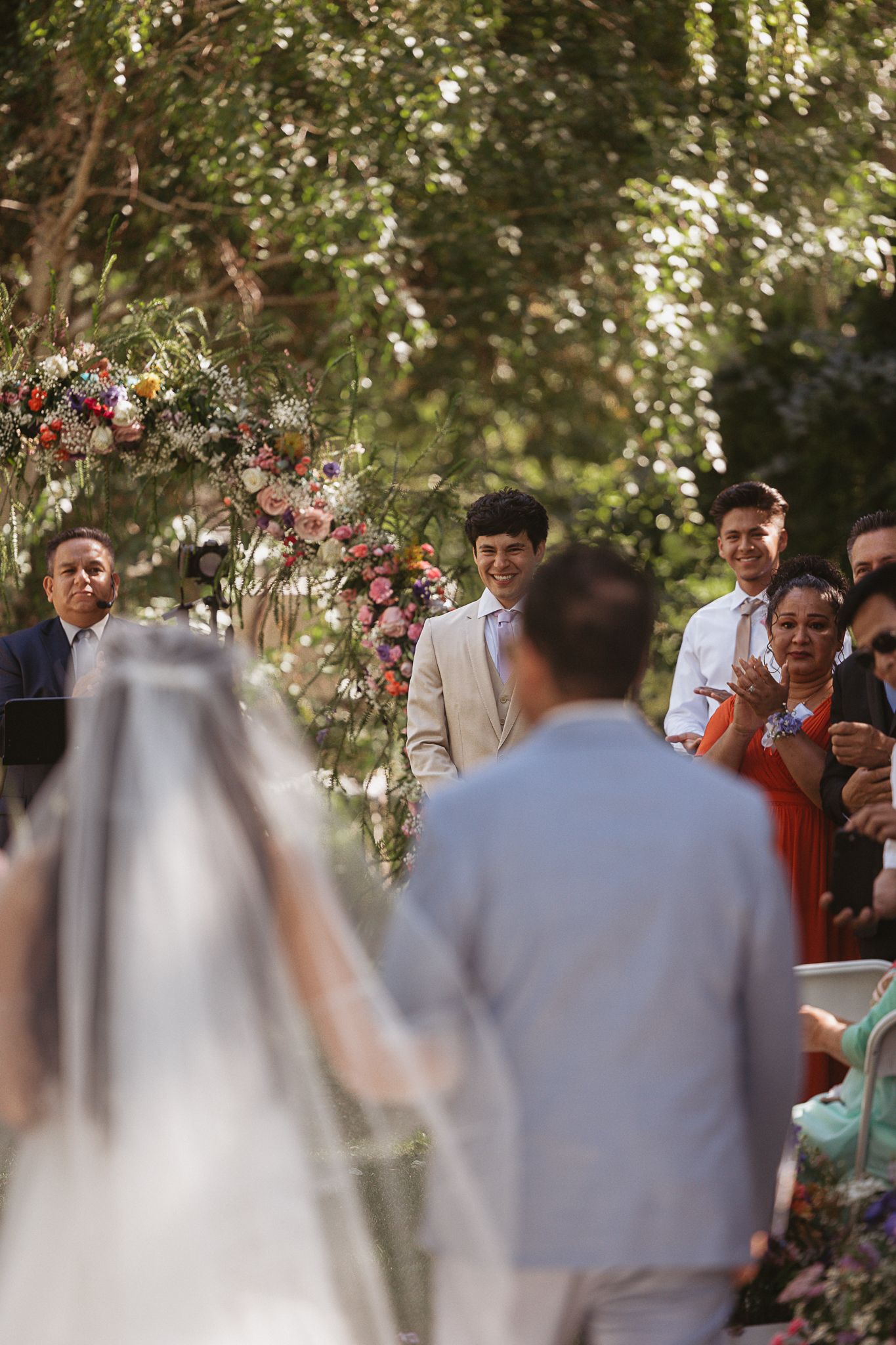 A couple in wedding attire shares an intimate moment against a backdrop of majestic mountains and evergreen trees.