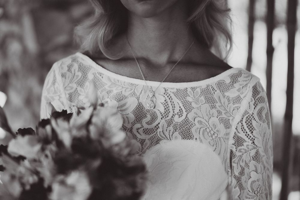 Close-up detail of delicate lace wedding dress with floral elements.