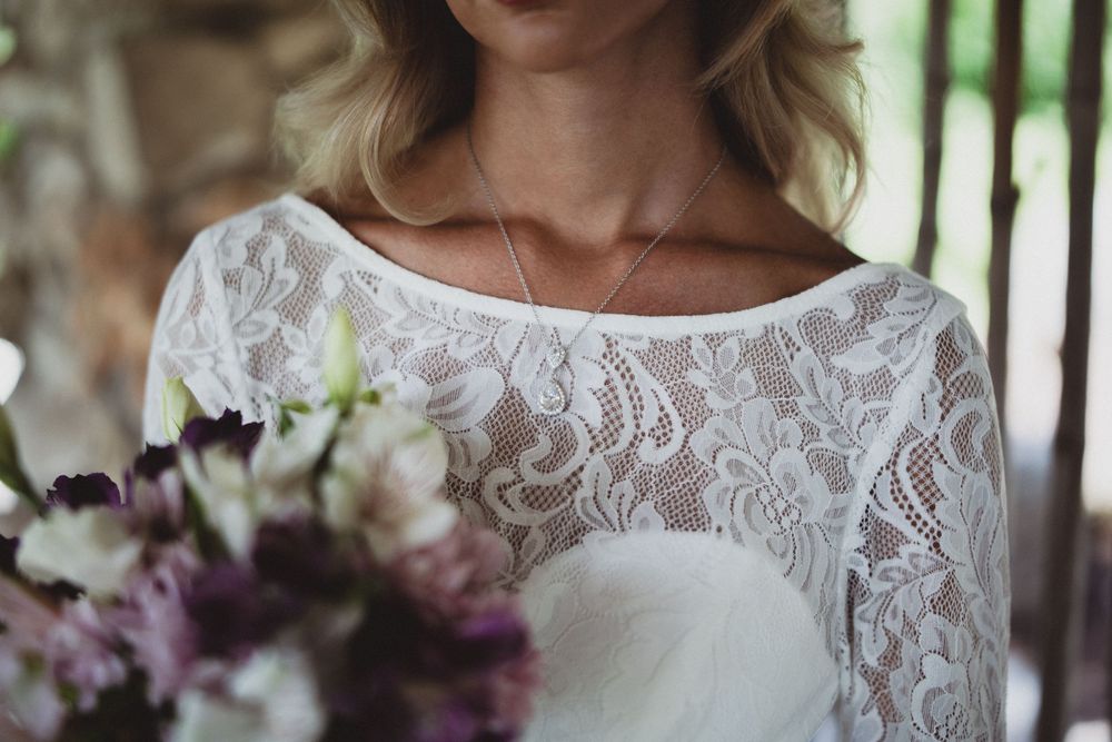 A bride wearing a delicate lace wedding dress with floral details and a sweetheart neckline.