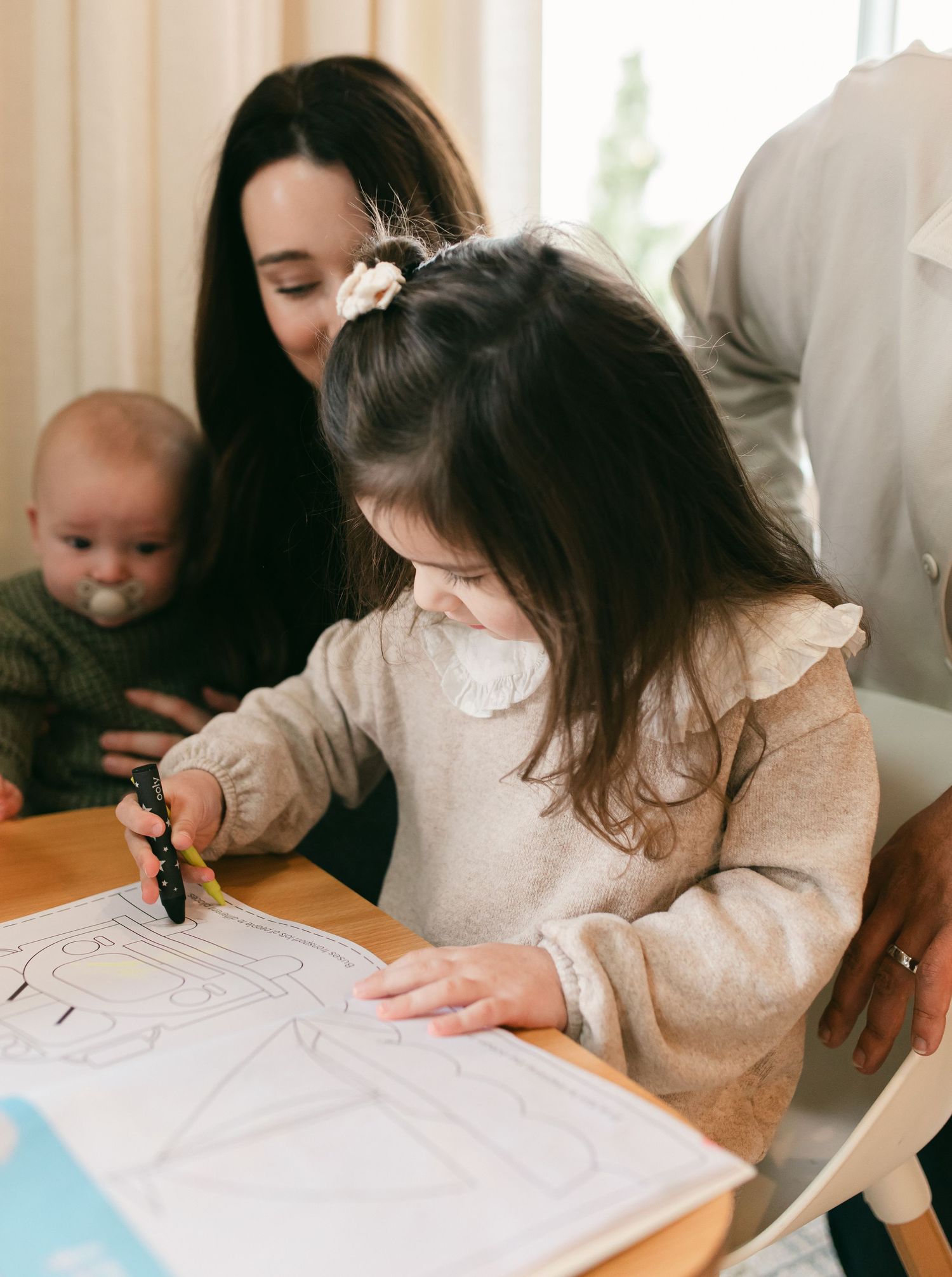 A child and adult work together on writing or drawing at a table in a well-lit room.