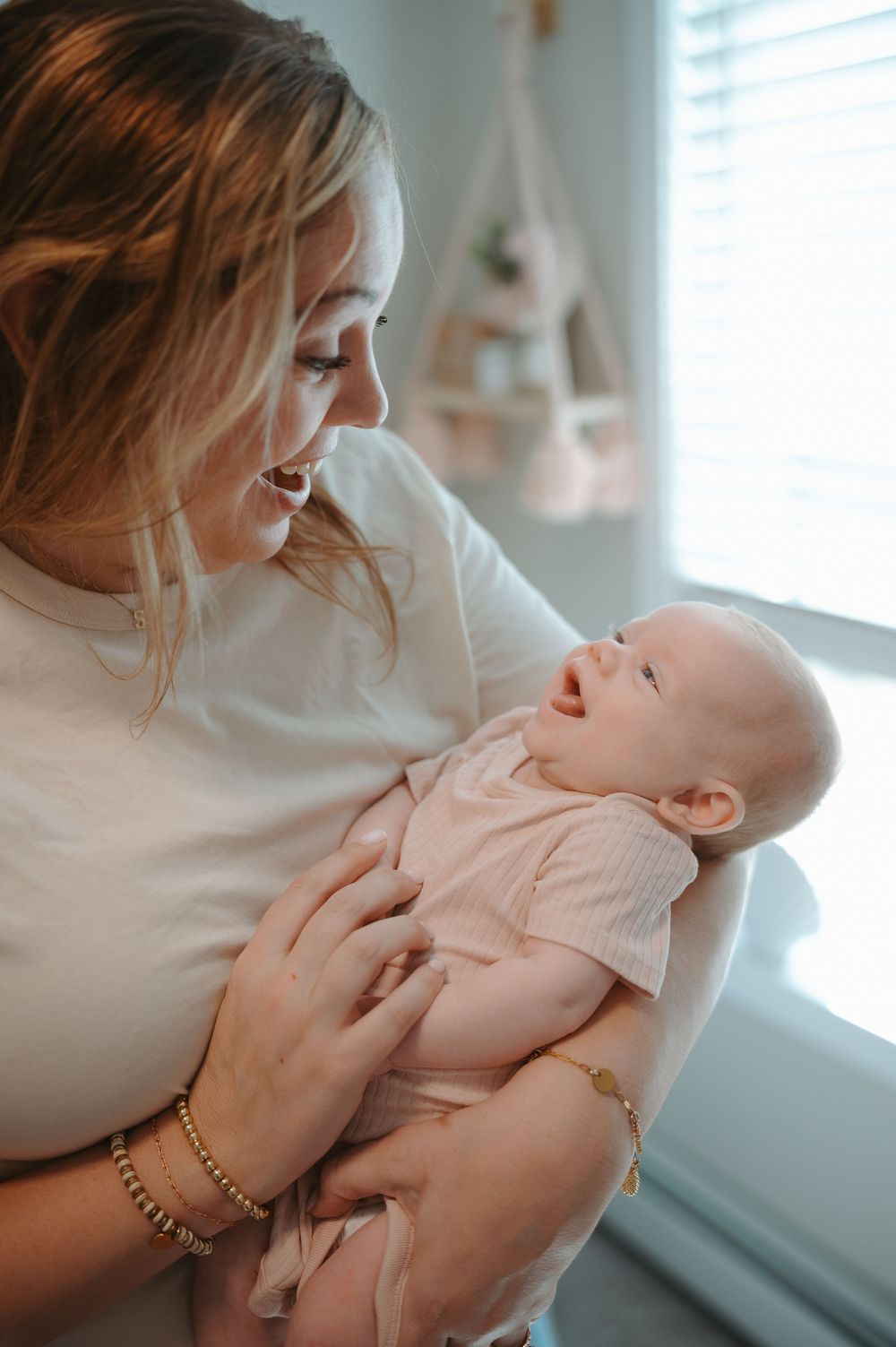 A tender moment between mother and baby in soft natural window light as they embrace and share affection.