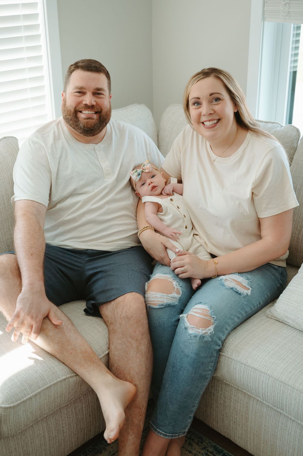 A family in matching white shirts sits together on a gray couch in a series of candid lifestyle photos.