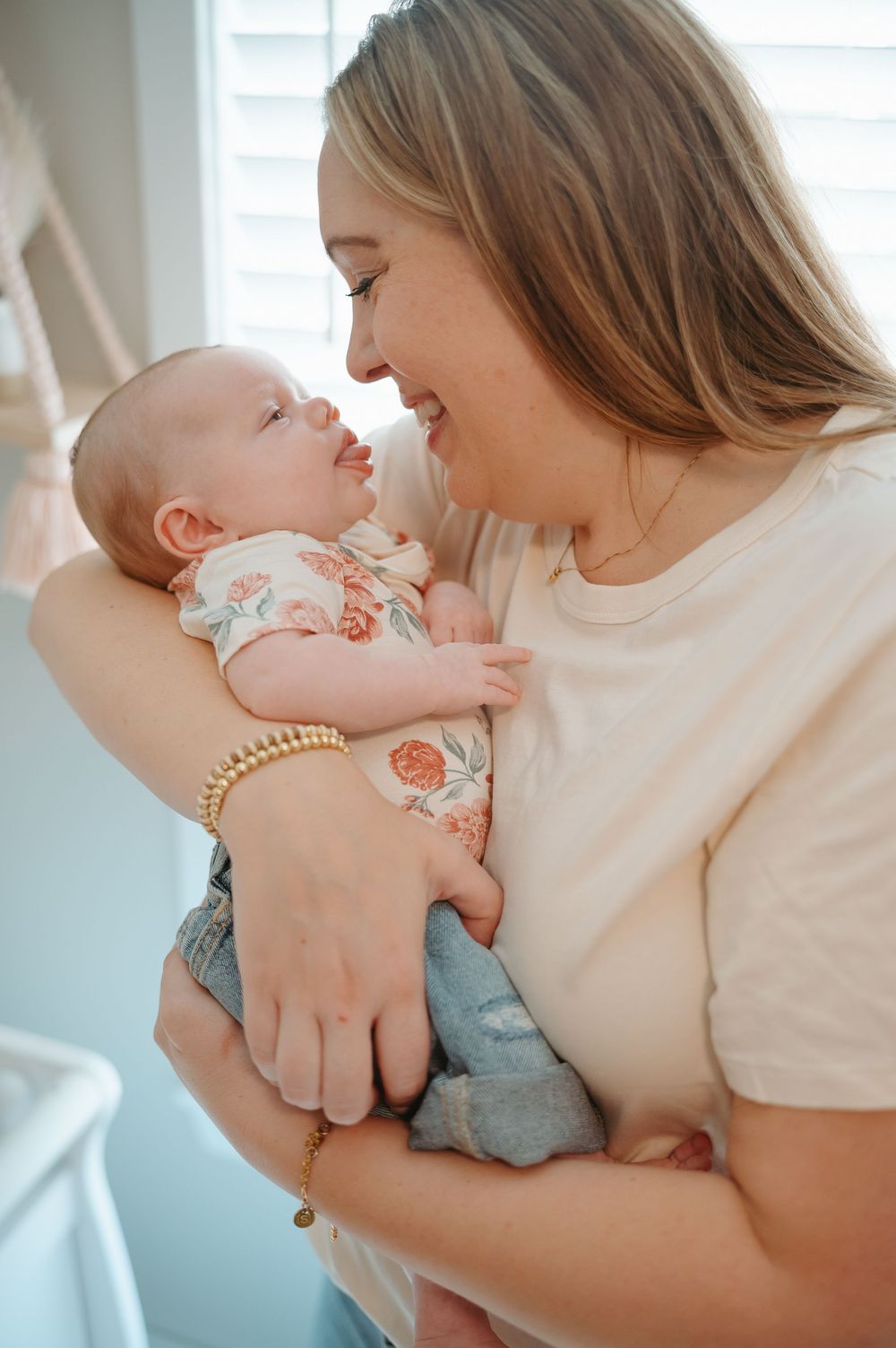 A tender moment between parent and baby in soft natural light as they embrace near a window.