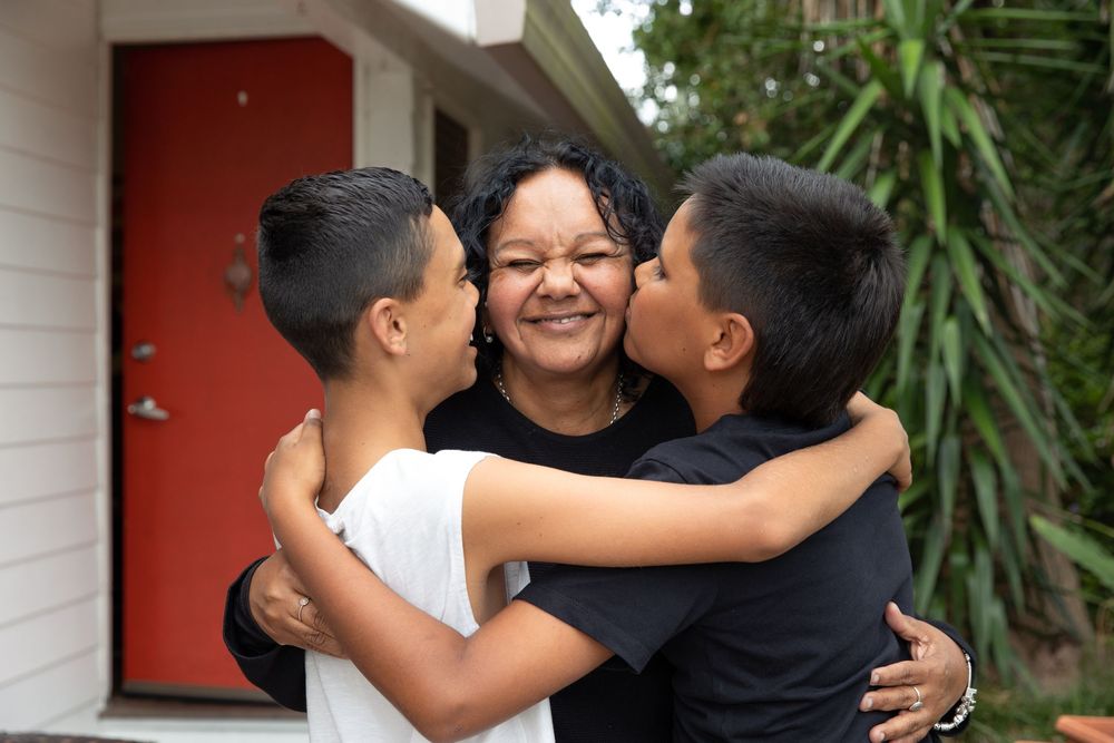 A sequence of four photos showing joyful embraces and reunions between family members outside a house.