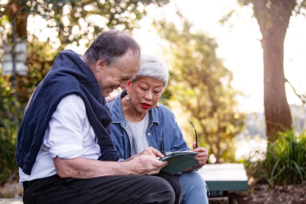 Two people sit together on a bench in a park during golden hour sunlight.
