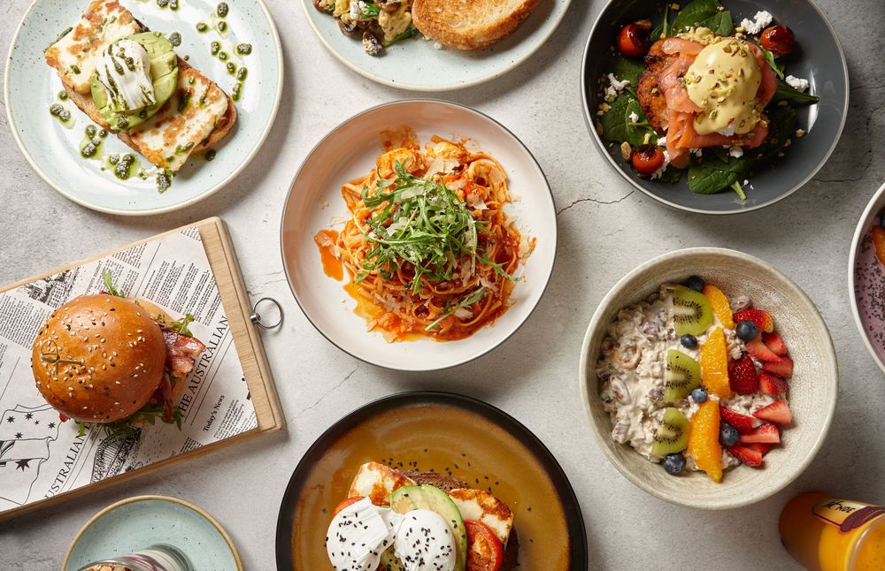 Overhead view of various restaurant dishes including burgers, salads, and appetizers arranged on plates and bowls.