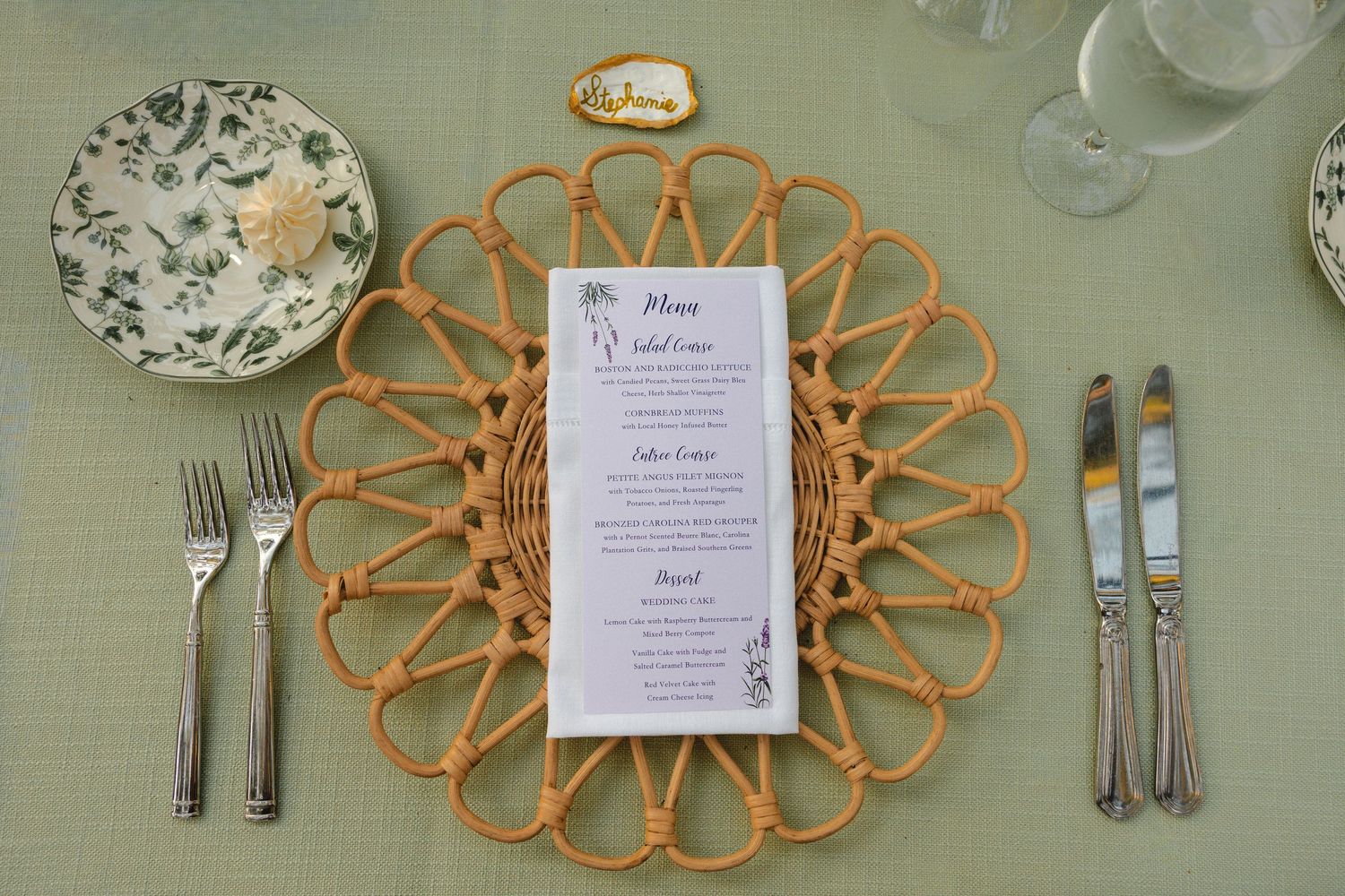 Place settings with vintage floral plates and decorative orange woven charger mats on mint tablecloth.