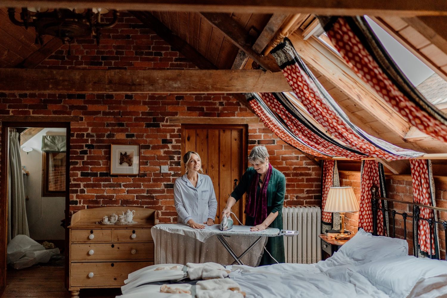 Cozy bedroom interior with exposed brick walls, vintage decor and striped fabric draping from the ceiling.