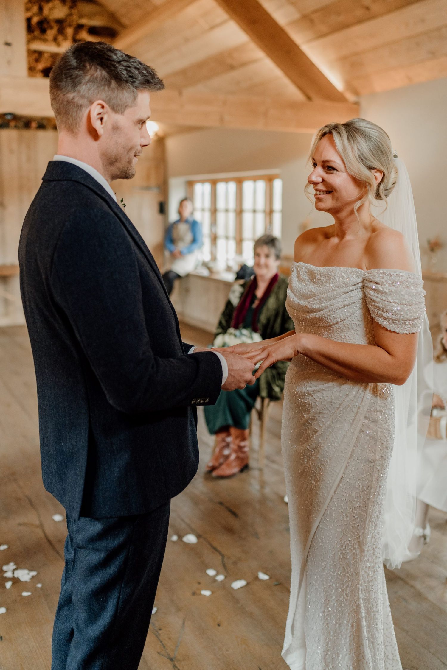 Couple exchanges rings during intimate ceremony in rustic wooden venue.