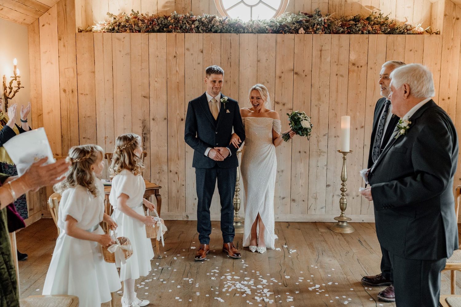 Panoramic view of a wedding ceremony inside a rustic wooden barn with natural lighting.