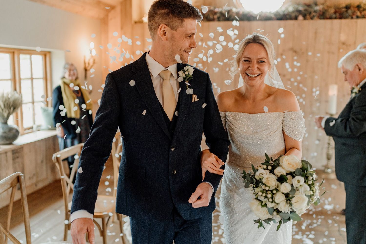 Wedding celebration photos in a warmly lit barn venue with floral decorations.