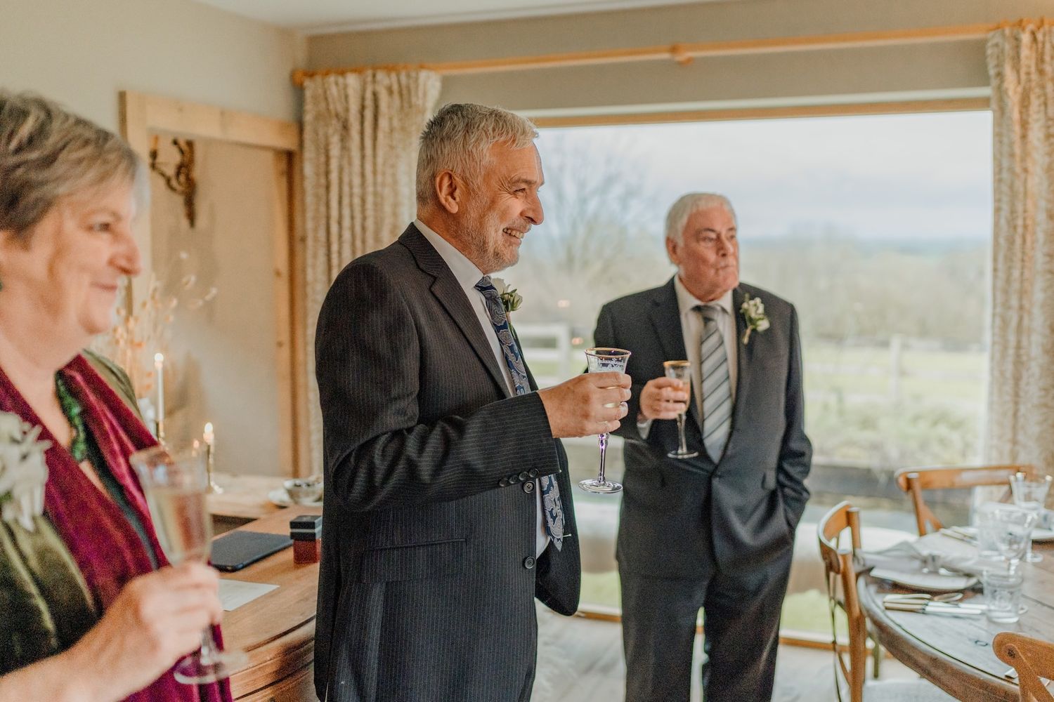Wedding guests enjoying an intimate indoor celebration with wine and conversation in an elegant dining room.