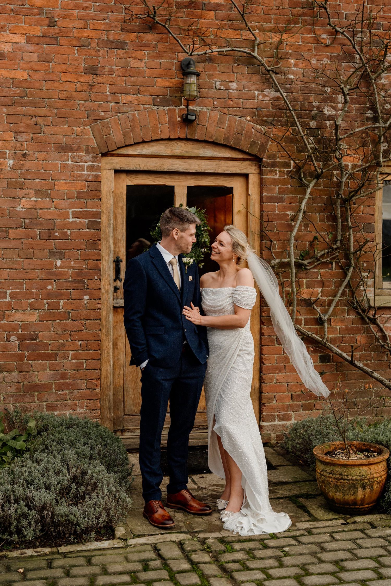 A romantic wedding photoshoot sequence against a rustic brick wall exterior with wooden door and potted plants.