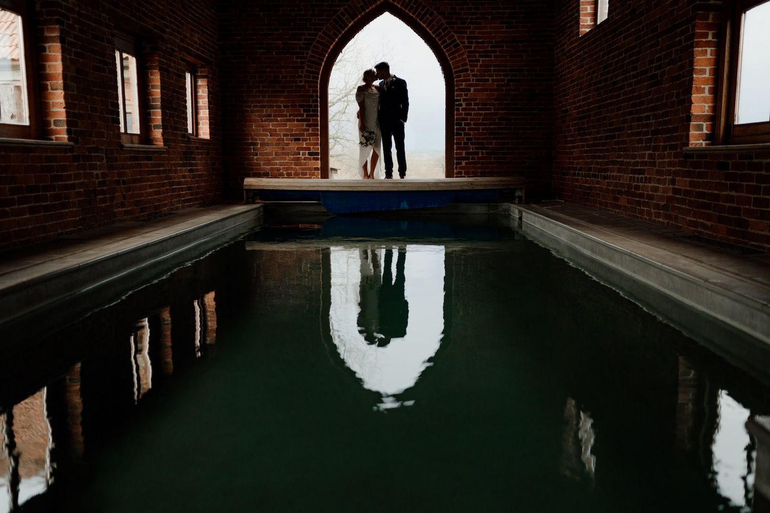 Dramatic silhouette of wedding guests in a Gothic-style brick church interior.