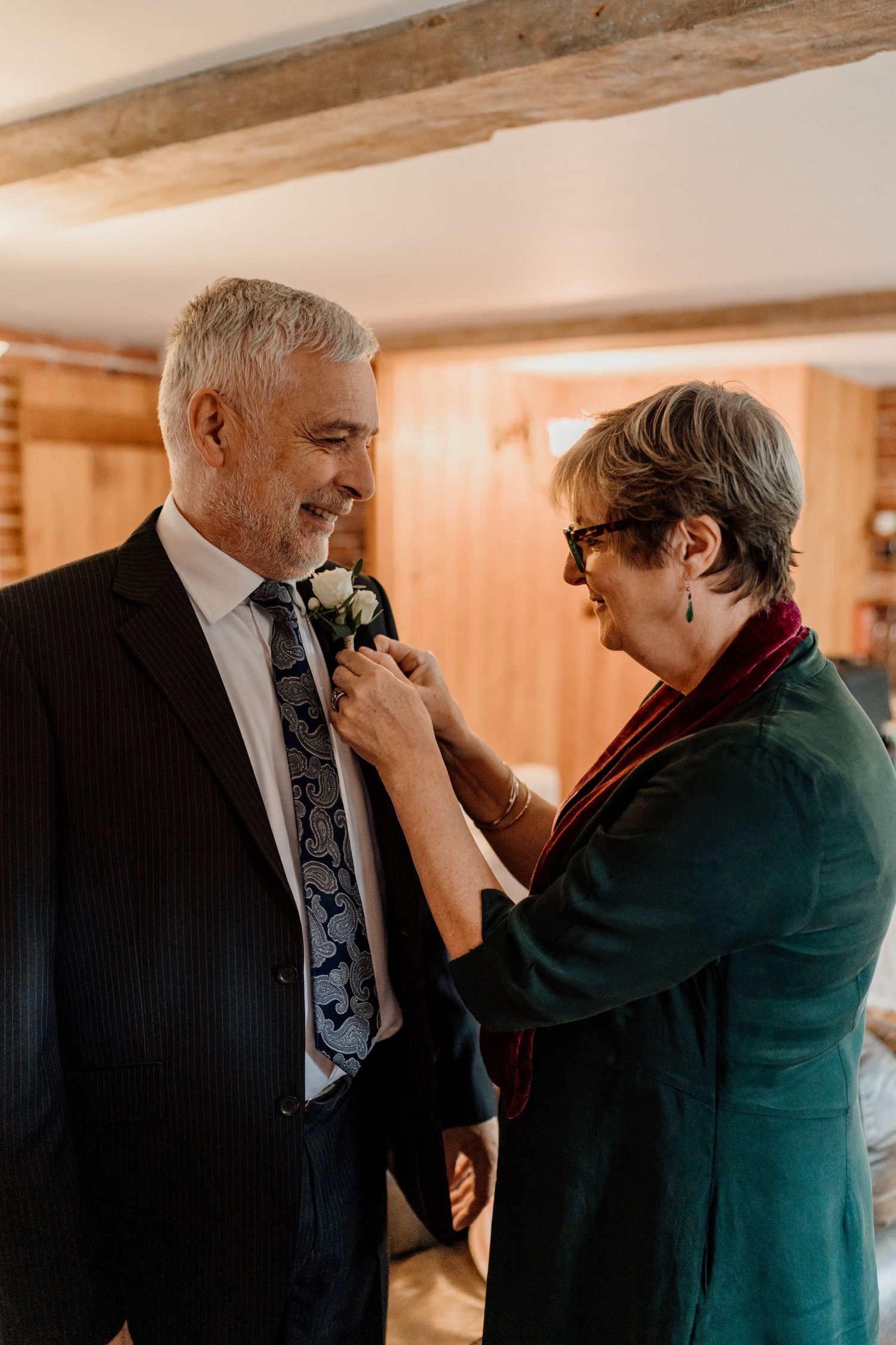 A heartfelt moment during a wedding ceremony as someone pins a boutonniere onto a dark suit.