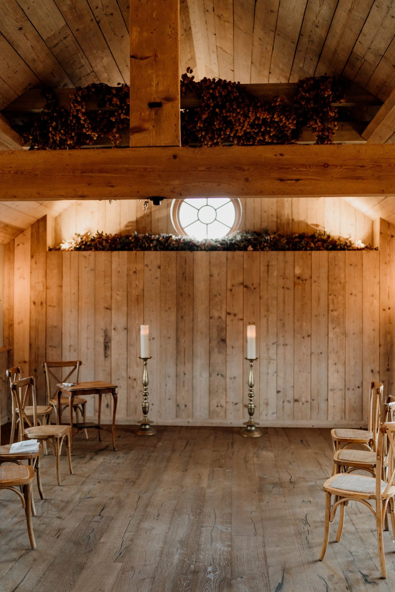 Rustic wooden barn venue set up for a wedding ceremony with simple chairs and natural lighting.