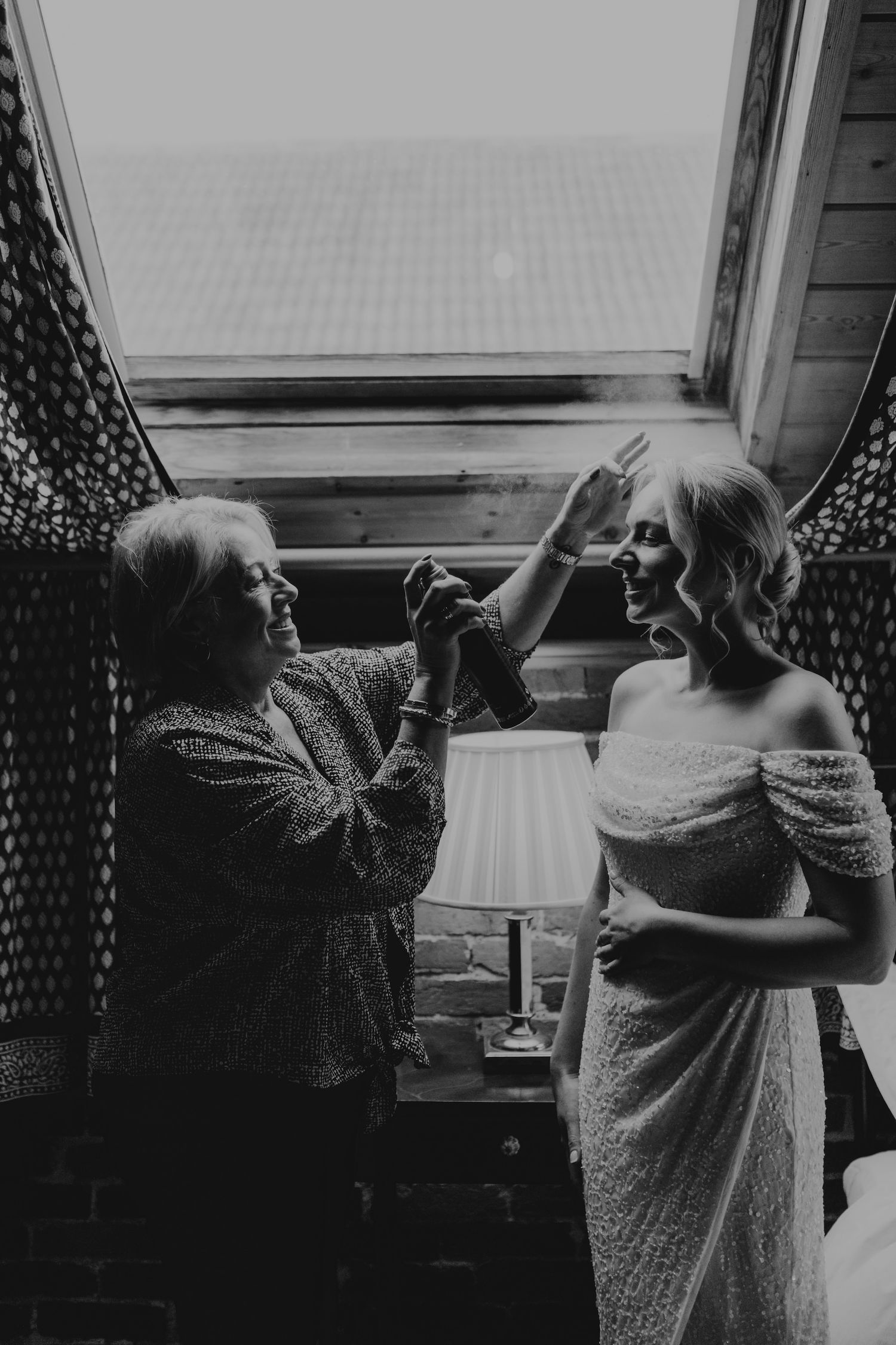 Black and white photo showing guests sharing drinks by a window.