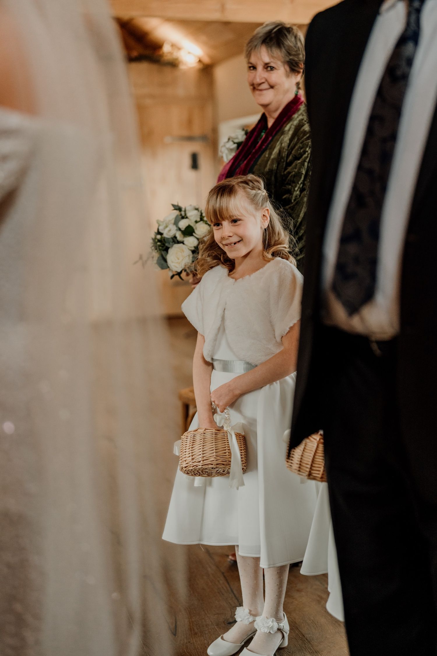 Young attendants in white dresses participating in a wedding ceremony.