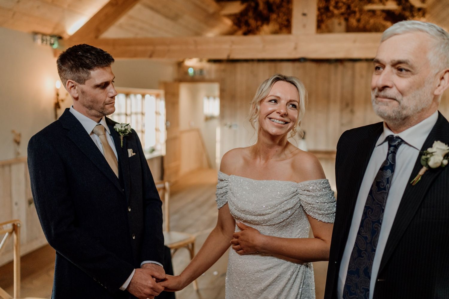 Wedding party members share joyful moments in a warmly lit wooden barn setting.