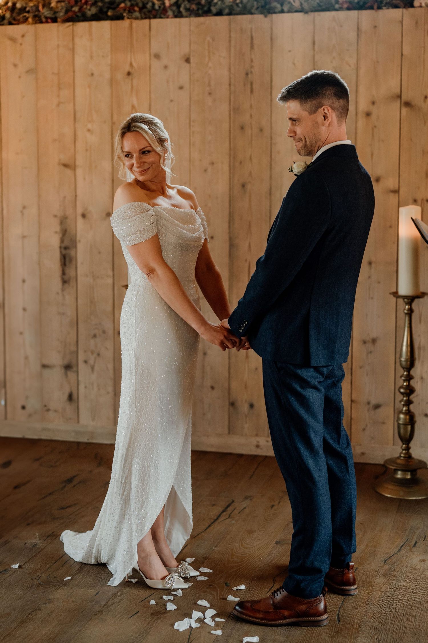Wedding couple dancing together in a rustic barn with wooden walls and candlelit ambiance.