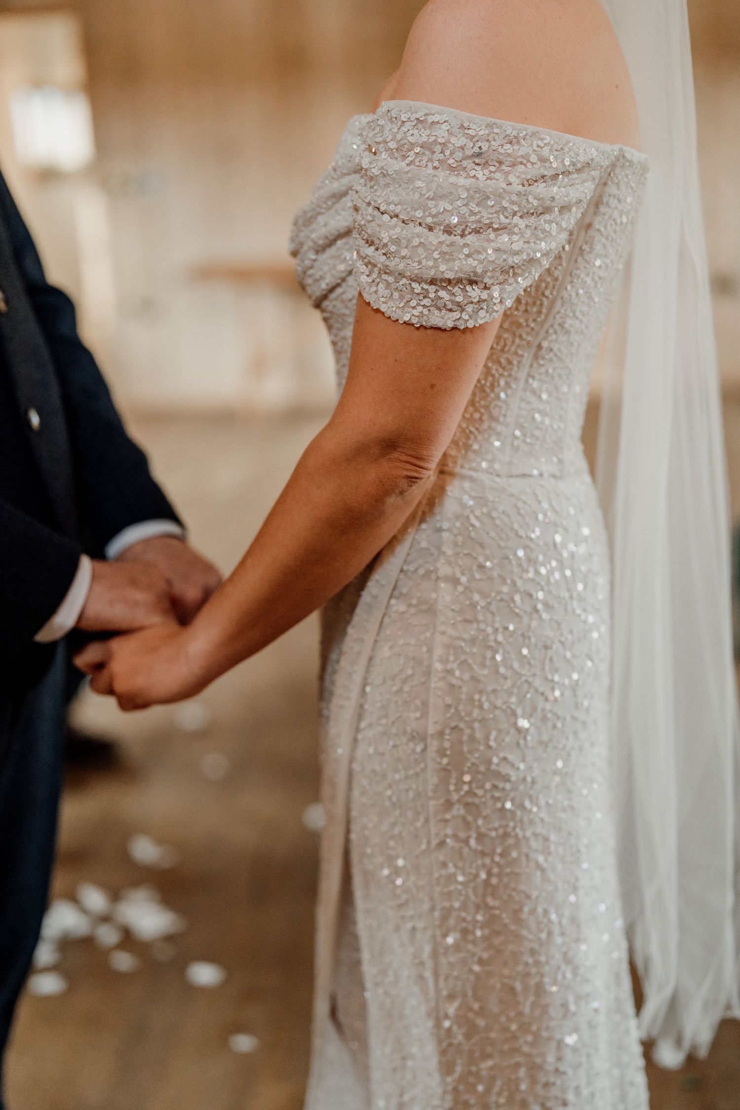 Close-up detail of a sequined off-shoulder wedding dress with flowing veil.